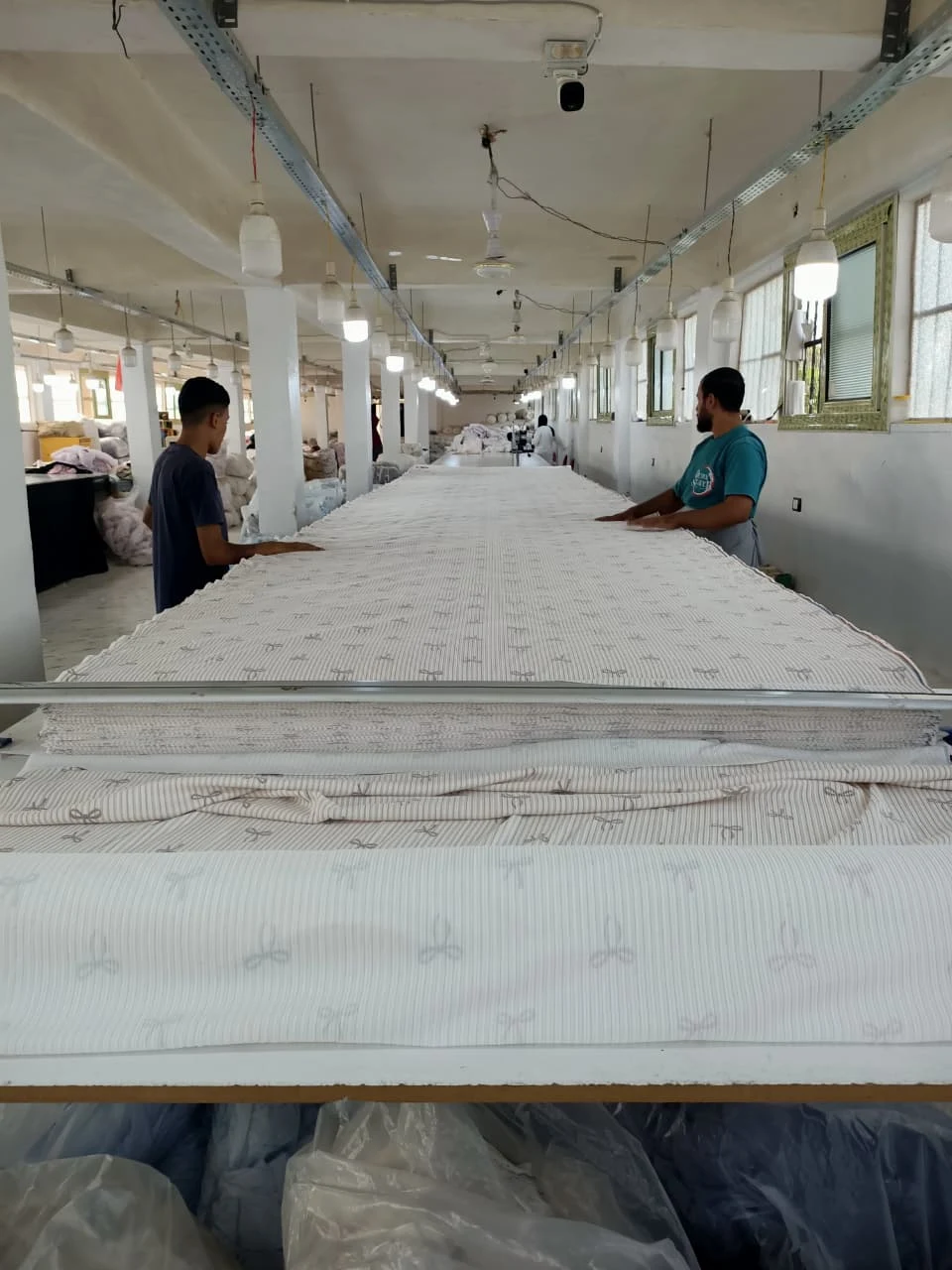 Two team members laying out fabric on a long cutting table