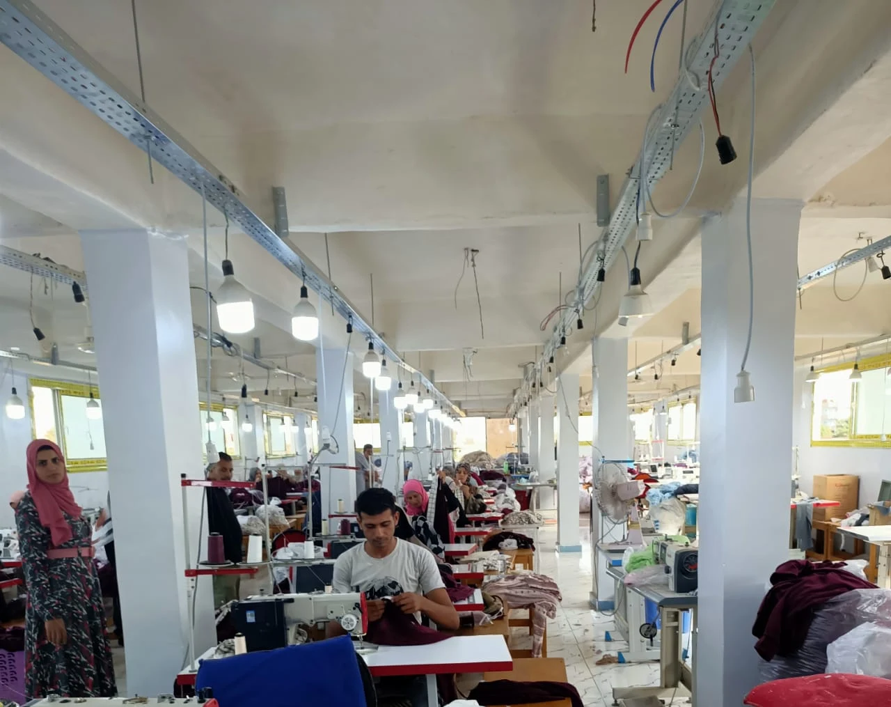 Garment makers working along rows of sewing machines